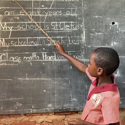 Child pointing at blackboard in classroom